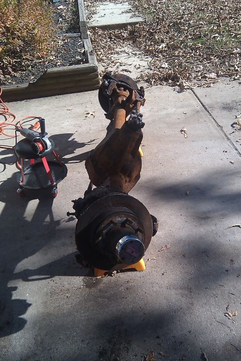 1996 Ford Bronco - A disassembled front axle assembly sits on yellow jack stands next to an angle grinder.