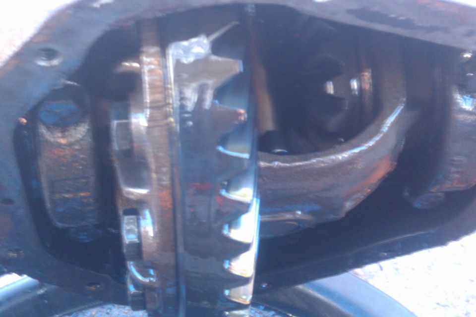 Close-up of differential gears with oil, showing wear and metal components