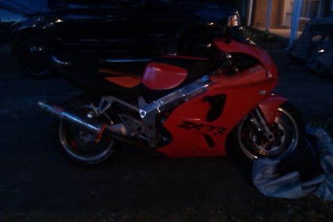 1996 Kawasaki Ninja R - A red 1996 Kawasaki Ninja motorcycle is viewed from the side, showing its distinctive fairing and exhaust.