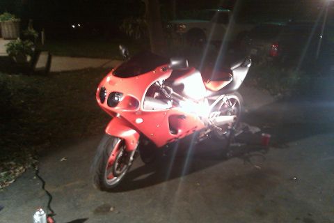 1996 Kawasaki Ninja R - A red sport motorcycle is parked outside at night, with its headlights on.