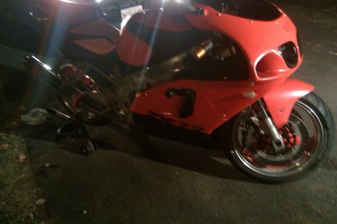 1996 Kawasaki Ninja R - A red motorcycle with a prominent number 7 graphic on its fairing is shown from a 3q-front angle.