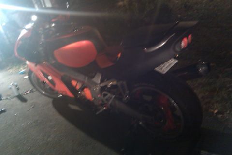 1996 Kawasaki Ninja R - A red and black sport motorcycle is parked on a paved surface at night, with grass and foliage in the background.