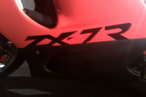 1996 Kawasaki Ninja R - Close-up of a red motorcycle fairing displaying a black ZX-7R decal.