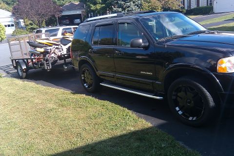 2005 Ford Explorer - A black 2005 Ford Explorer is seen from the side, towing a trailer loaded with jet skis.
