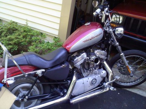 2004 Harley-Davidson Sportster Custom - A red and silver Harley-Davidson Sportster Custom motorcycle is parked in a garage.