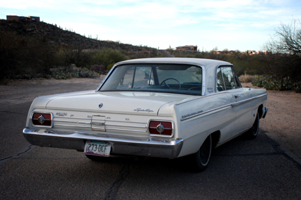 1965 Ford Fairlane - Rear view of a white 1962 Ford Fairlane with a desert background and scrub brush landscape in the background.