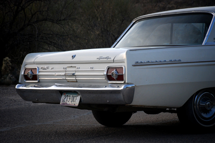 1965 Ford Fairlane - Rear view of a white 1965 Ford Fairlane 500 sedan, showing its distinctive taillights and chrome bumper.