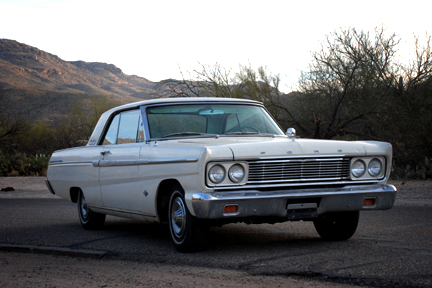 1965 Ford Fairlane - A white 1964 Ford Fairlane is parked outdoors with a mountainous desert landscape behind it.