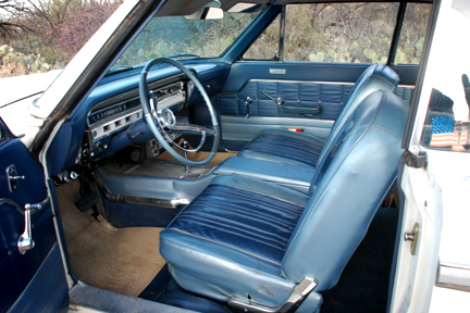 1965 Ford Fairlane - The interior of a 1965 Ford Fairlane shows blue vinyl seats and a dashboard with a classic steering wheel.