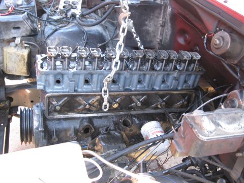 1981 Ford Bronco - Engine compartment with engine partially disassembled and suspended by a chain. An oil filter is visible.