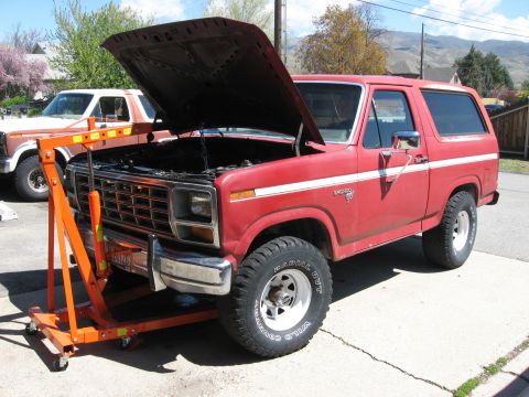 1981 Ford Bronco - A red Ford Bronco, likely from the late 1970s, is parked with its hood up next to an engine hoist.