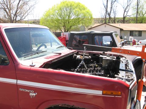 1981 Ford Bronco - A red 1981 Ford Bronco is shown with its engine removed and an engine hoist positioned over the engine bay.