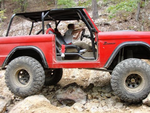 1967 Ford Mustang - A red first-generation Ford Bronco navigates a challenging rocky terrain off-road.