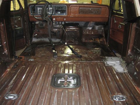 1979 Ford Bronco - The interior of a 1979 Ford Bronco shows extensive disassembly and rust damage, with evidence of floor repairs.
