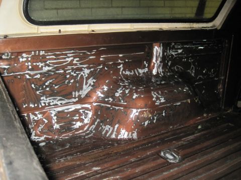 1979 Ford Bronco - The interior of a truck bed shows signs of work with white residue on the brown painted surface.