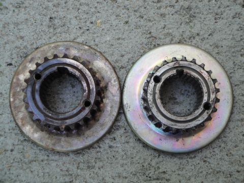 1995 Ford Taurus - Two metal sprockets, one appearing more worn than the other, are displayed side-by-side on a textured concrete background.