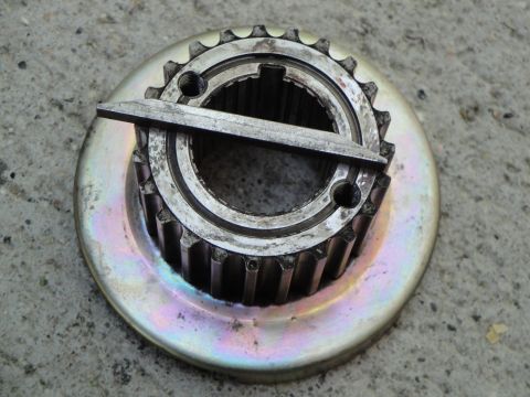 1995 Ford Taurus - A metal pulley with gear teeth, possibly a crankshaft pulley, is shown resting on a concrete surface.