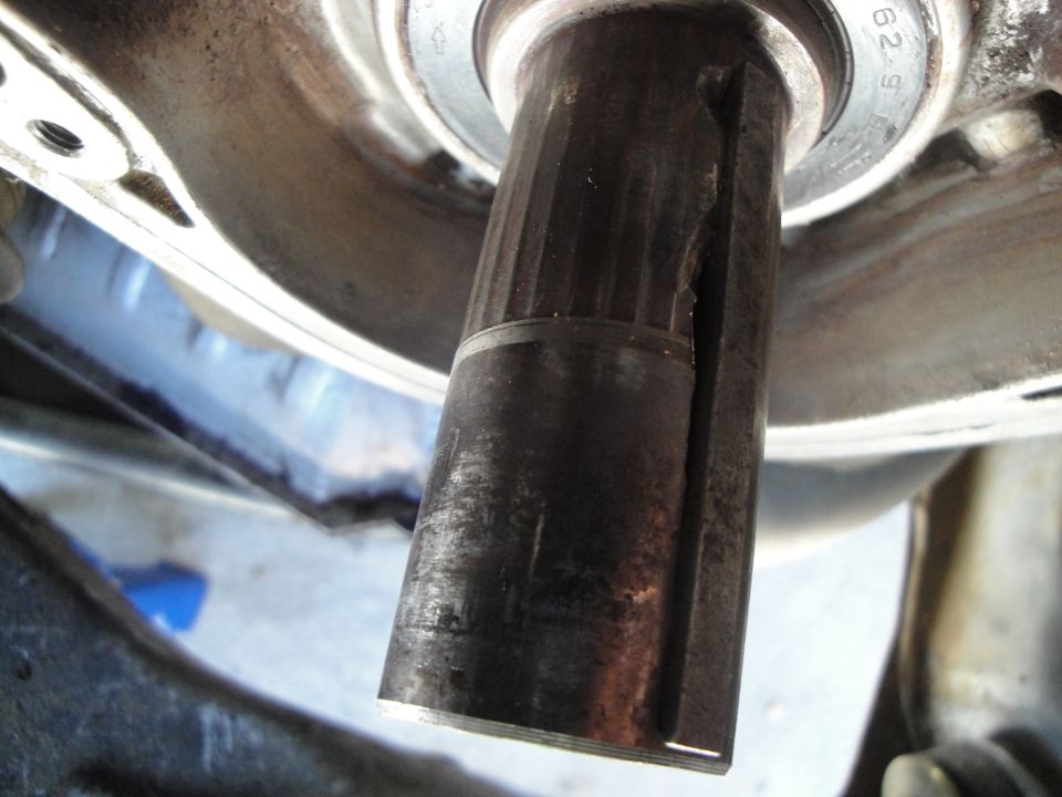 Close-up of a damaged metal shaft with a split and visible wear marks