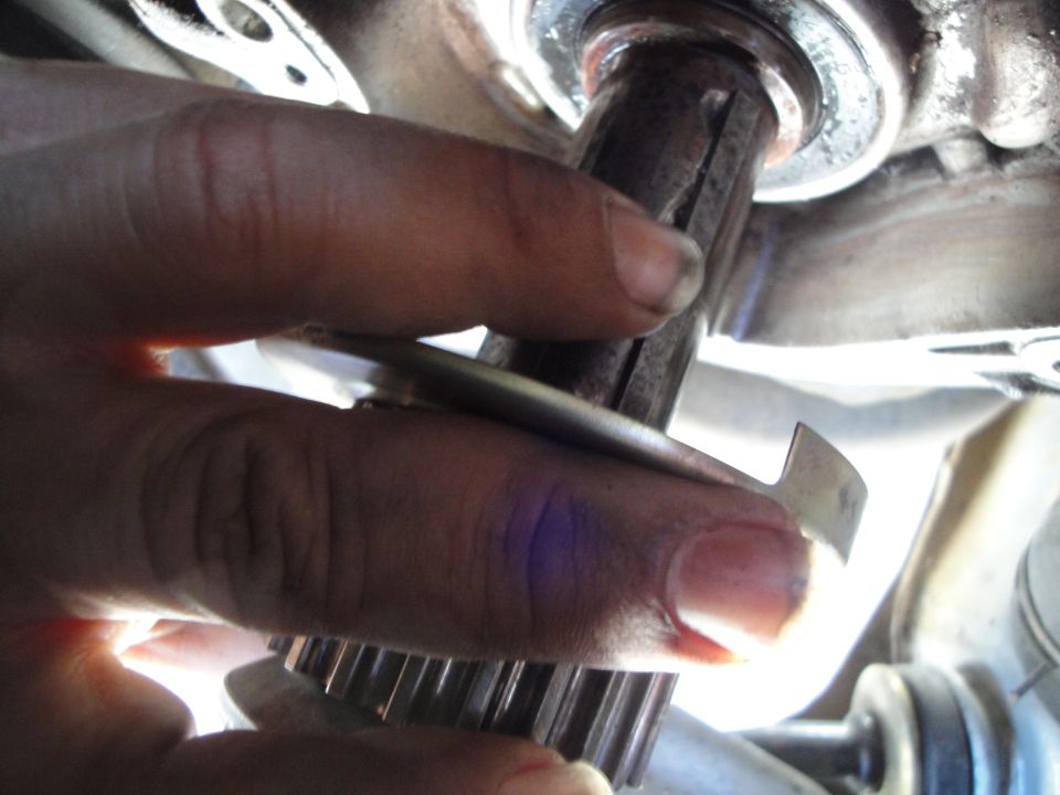Hand holding a splined metal gear near a shaft
