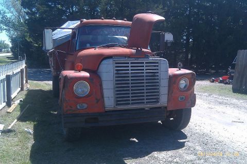 2000 Mercury Grand Marquis - An old orange dump truck sits parked outdoors with its hood raised.