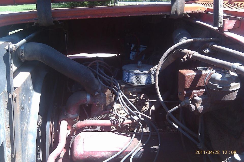 Engine bay of an older truck, showing hoses, air filter, and engine block