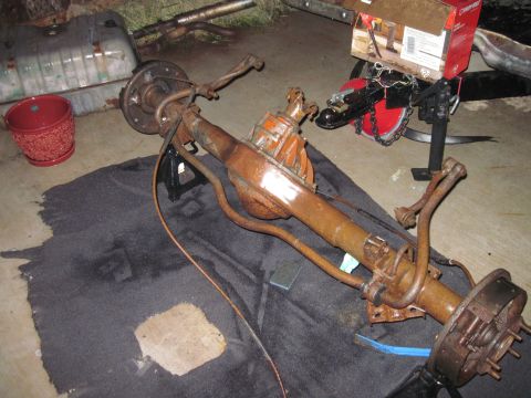 1979 Ford Bronco - A rusty rear axle assembly with brake drums and suspension components is shown on jack stands.