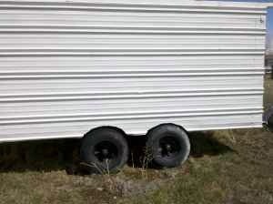 2006 Ford E350 - Side view of a white trailer with a corrugated metal exterior and two wheels.