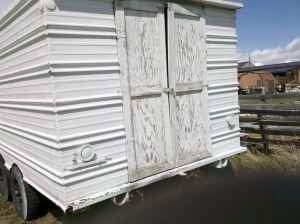 2006 Ford E350 - A white trailer with a weathered appearance sits outdoors under a clear blue sky.