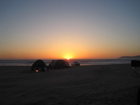 1989 Ford Bronco - Camping on the beach at sunset with tents and vehicles.