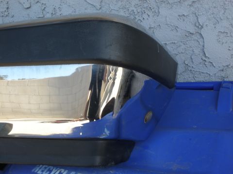 1989 Ford Bronco - Chrome bumper part with black trim sits on a blue plastic object.