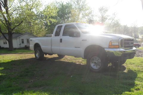 2000 Ford F-250 - This white crew cab pickup truck is shown from a 3/4 front angle.
