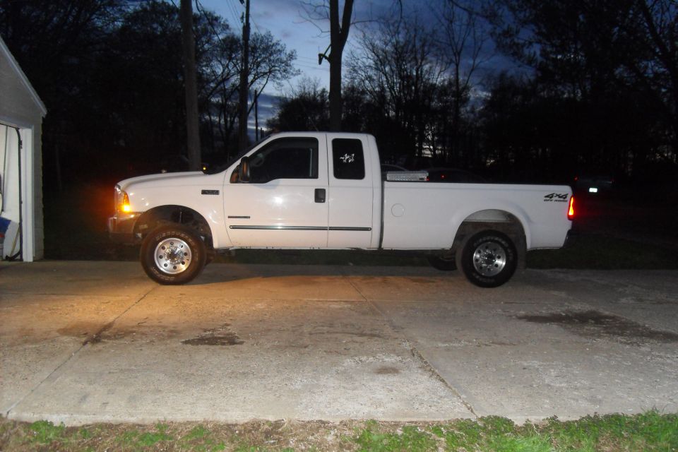 White 2000 Ford F-250 truck, side view, parked on concrete driveway at dusk