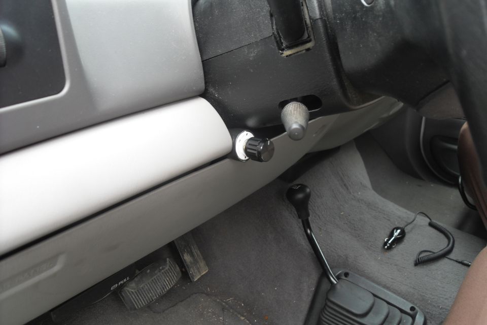 Interior view of a truck's dashboard with two aftermarket knobs installed near the steering column and a gear shifter