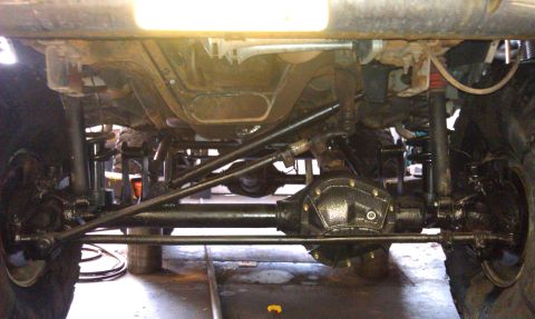 1996 Ford Bronco - The photo shows the undercarriage of a vehicle, focusing on the front axle and suspension system.