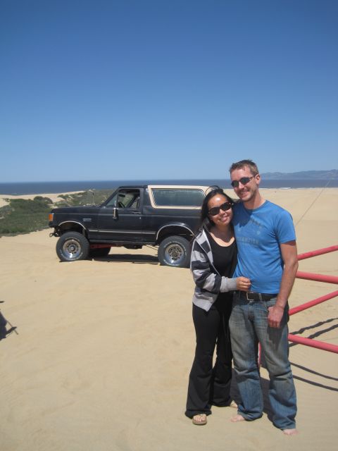 1989 Ford Bronco - Couple poses with their 1989 Ford Bronco on a sandy dune overlooking the ocean.