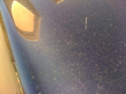 1985 Ford Mustang - Close-up of blue car paint shows dust and imperfections.