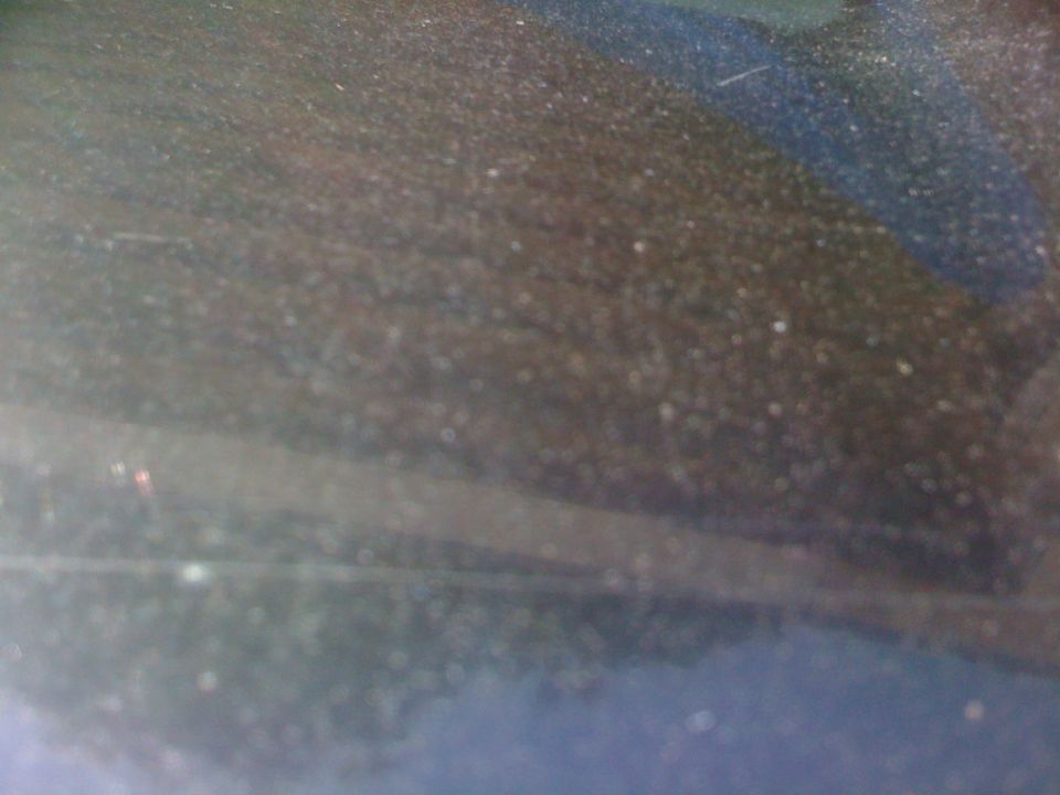 Dusty dark surface with small white specks and a blurry blue stripe