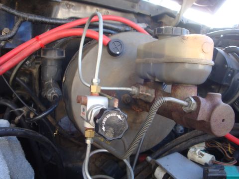 1989 Ford Bronco - Close-up of a vehicle's brake booster and master cylinder assembly, a knob labeled 'LESS BRAKE'.