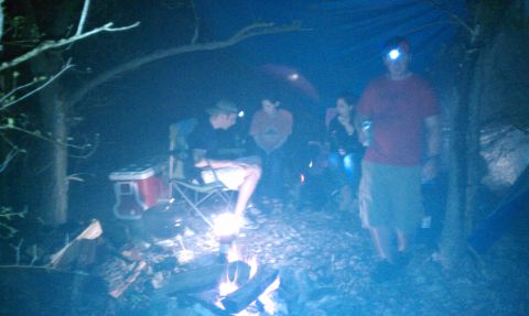 2005 Jeep Wrangler - Campfire scene at night with several people and camping gear.