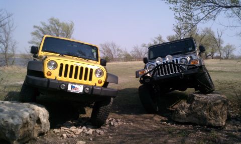 2005 Jeep Wrangler - Two Jeep Wranglers navigate rocky terrain under a clear sky.