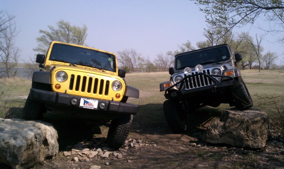 Yellow and black Jeep Wranglers on rocks. The yellow one has a US flag license plate frame