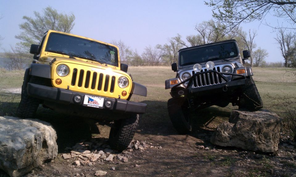 Yellow Jeep Wrangler and silver Jeep Wrangler off-roading over rocks