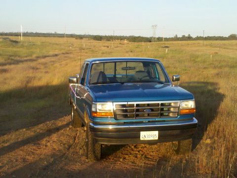 1992 Ford F-150 - This blue 1992 Ford F-150 is parked in a field with a clear sky overhead.