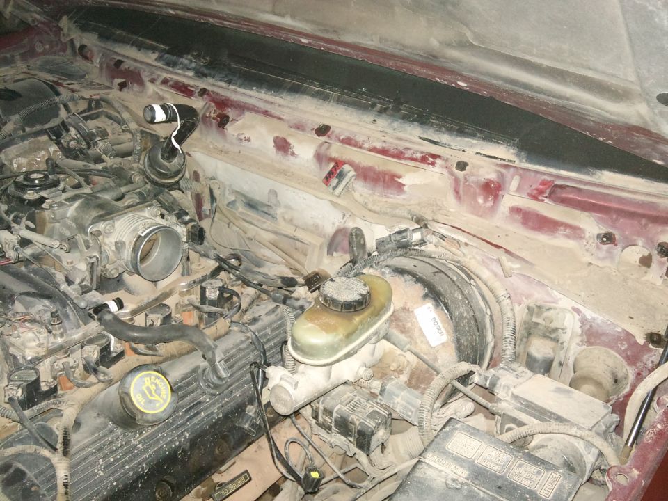 Engine bay with brake fluid reservoir and throttle body visible. Dusty interior