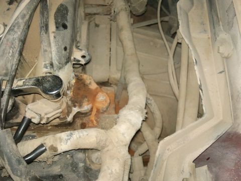 1998 Ford Crown Victoria - Underside view of engine bay components, showing hoses, wiring, and metal parts with accumulated dirt.