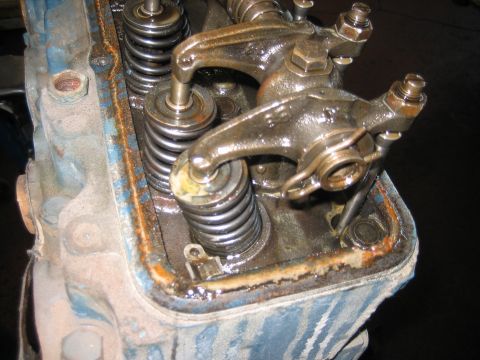 1998 Ford Crown Victoria - Close-up of a rusty inline engine's exposed valve springs and rocker arms with old blue paint and surface rust.