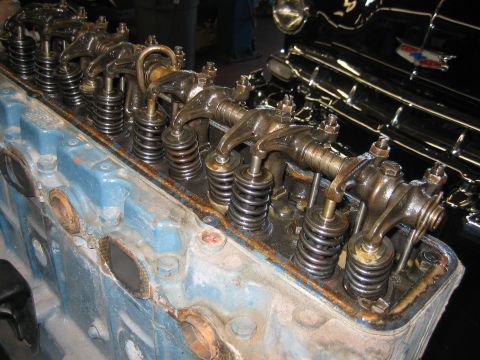 1998 Ford Crown Victoria - Several rocker arms and valve springs stand in a row atop a blue-painted inline engine head undergoing rebuild.