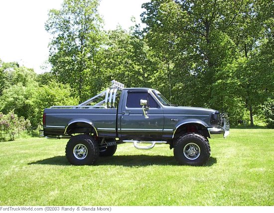 Lifted grey Ford F-150 regular cab 4x4 side view on grass with chrome wheels and side exhaust