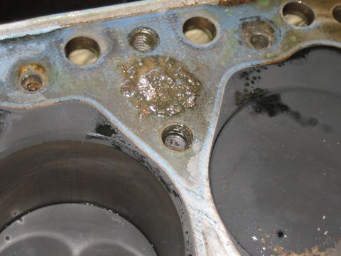 1998 Ford Crown Victoria - Macro view of an engine block deck showing a heavily corroded coolant passage between two cylinder bores and threaded bolt holes.