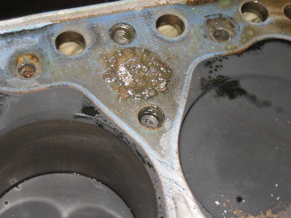 Close-up of engine block deck surface with corroded coolant passage and head bolt holes